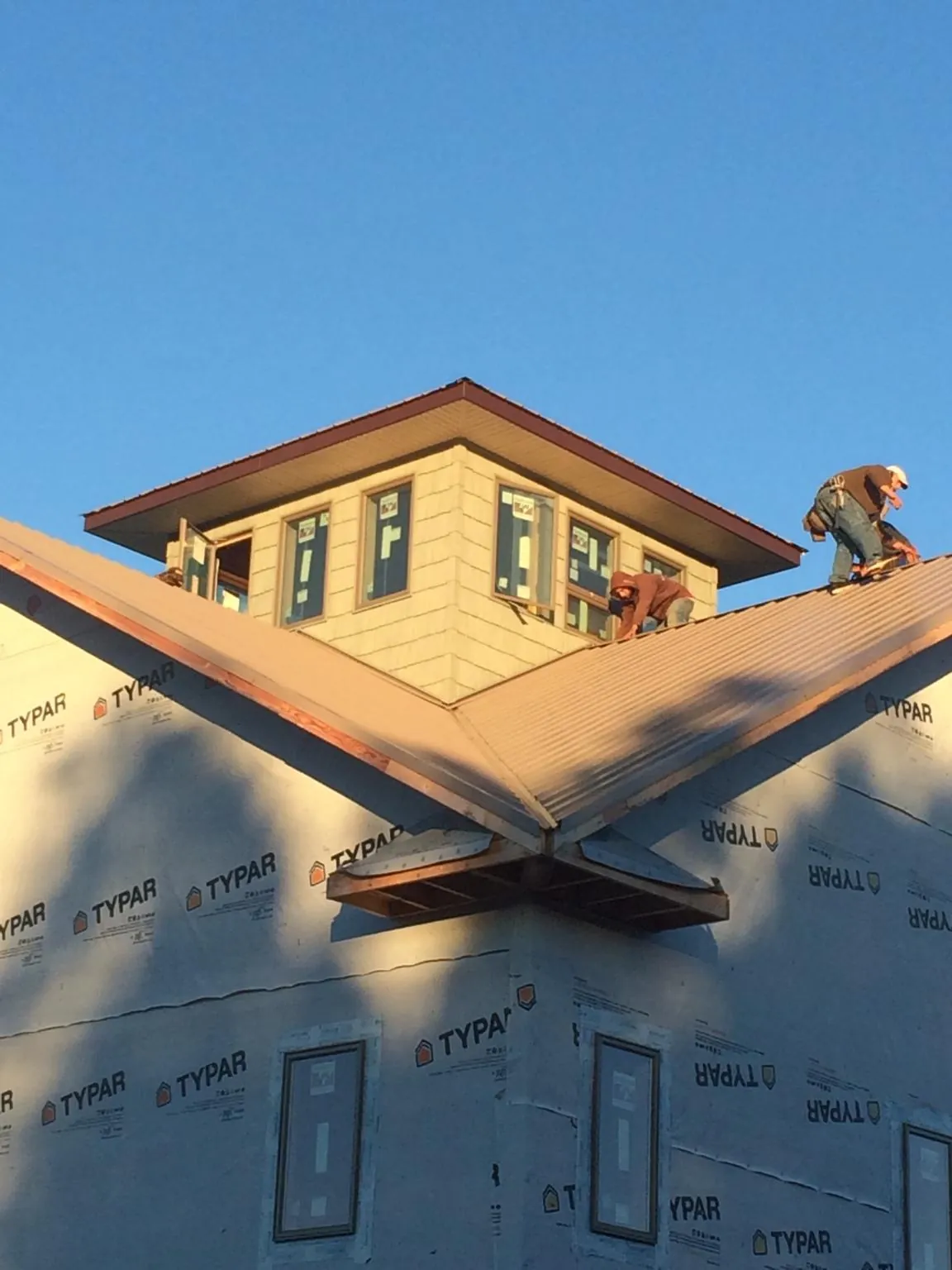 Roofers working around a rooftop cupola on a new metal roof at sunset — Roof Waterproofing in Patterson by Roofing Brothers
